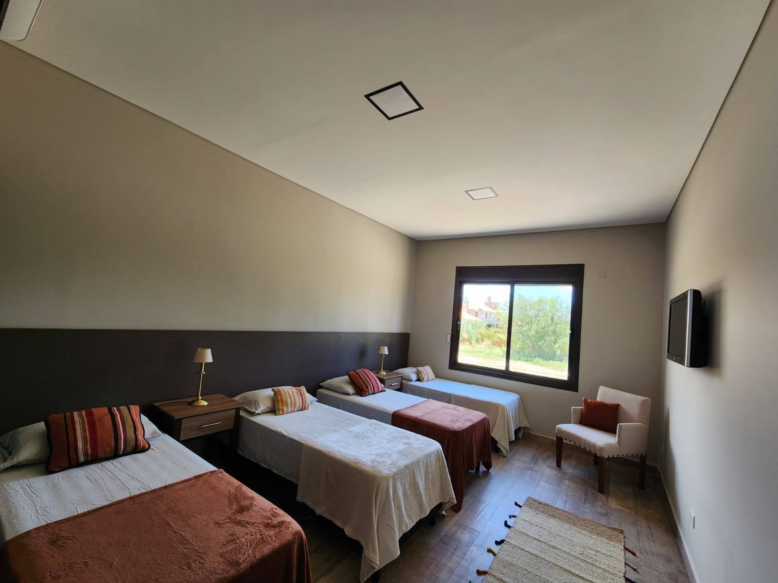 Quarto quádruplo com camas de solteiro e detalhes em madeira — projeto Ca La Estancia, por Luciana González Anderson, em Cafayate